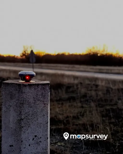 Antena GNSS sobre un pilar geodésico al atardecer